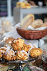 Croissants with basket of bread loaf in background