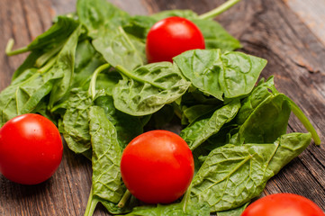 Fresh tomatoes and spinach on wooden table