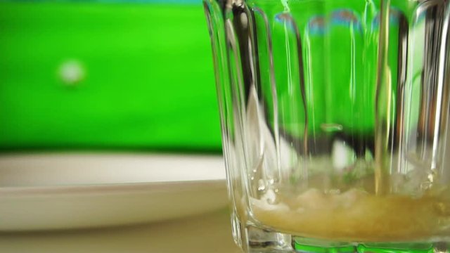 beer and snacks. Watching football with beer and pistachios. Beer is poured into a glass and pistachios fall into a plate close up slow motion.