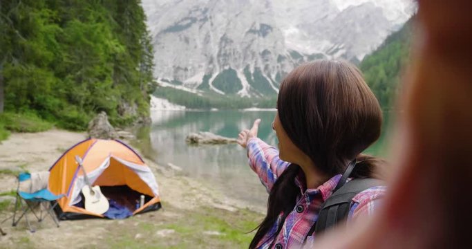 A woman makes a video call to friends, relatives or boyfriend to show him the beautiful place where camp with the tent. Concept of: trekking, technology, social network