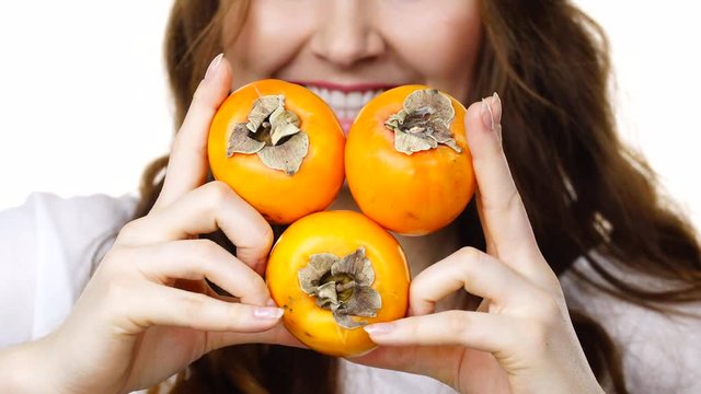 Woman toothy smile brunette girl holding  persimmon kaki fruits in hands, isolated on white. Healthy eating, vegetarian food, diet concept