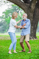 Elderly man have chest pains or heart attack in the park with senior woman, health care concept.
