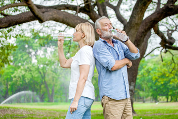 Fototapeta premium Happy elderly couple enjoying drink water in bottle of clean at the park, health care concept.