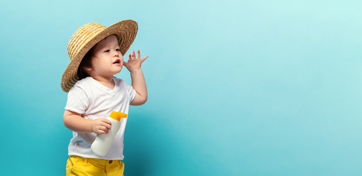 Toddler boy with a bottle of sunblock on a blue background