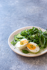 Fresh salad and boiled eggs on grey stone background