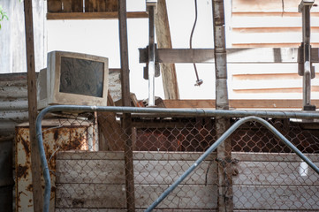 An abandoned CRT computer monitor, covered in dust, in an abandoned and falling down building