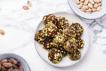 Homemade healthy vegan chocolate avocado truffles with pistachio in the bowl and ingredients on grey marble table. Organic energy vegetarian sweet balls