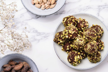 Homemade healthy vegan chocolate avocado truffles with pistachio in the bowl and ingredients on grey marble table. Organic energy vegetarian sweet balls