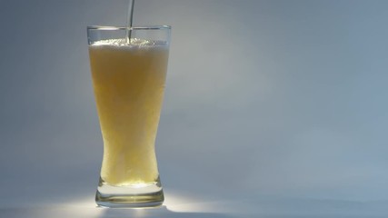 Slow motion of pouring beer in clear glass creating many bubbles. The shot continue revealing the foam of the beer overflowing the glass. - Powered by Adobe