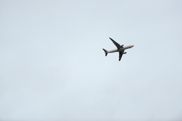 Fototapeta na wymiar Airplane with gear down against a pale blue sky