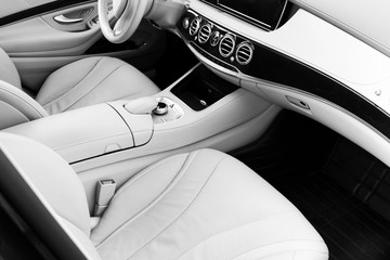 White leather interior of the luxury modern car. Leather comfortable white seats and multimedia. Steering wheel and dashboard. automatic gear stick. Black and white