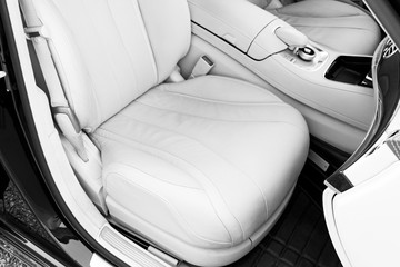 White leather interior of the luxury modern car. Leather comfortable white seats and multimedia. Steering wheel and dashboard. automatic gear stick. Car detailing. Black and white