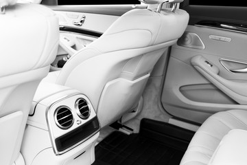 White leather interior of the luxury modern car. Leather comfortable white seats and multimedia. exclusive wood and metal decoration. Modern car interior details. Car detailing. Black and white