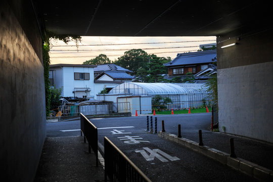 Dark Tunnel Looking Out On To Small Neighborhood Farm In Japanese Suburb - Text On Street Reads [Stop]