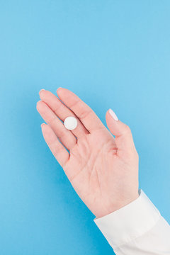 Female hand holding a white pill