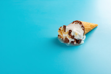 mini Vanilla flavor ice cream cone in a melting process on blue background