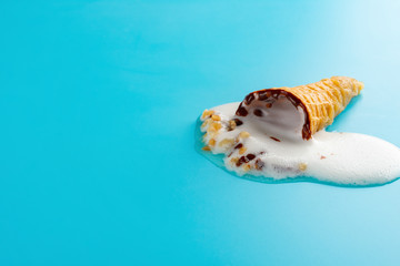 mini Vanilla flavor ice cream cone in a melting process on blue background