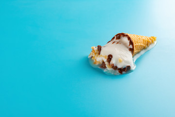 Obraz na płótnie Canvas mini Vanilla flavor ice cream cone in a melting process on blue background