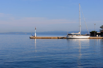 A harmonious image of a yacht and a fishing man at a dock. Isola, Slovenia