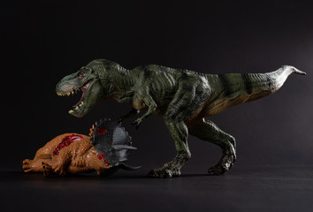 tyrannosaurus with a triceratops body nearby on dark background