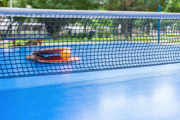 pingpong rackets and ball and net on a blue pingpong table