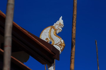 Fototapeta na wymiar Northern Thai Buddhist temple gable roof architectural ornamental details. delicate religious art work details against clear blue sky background.