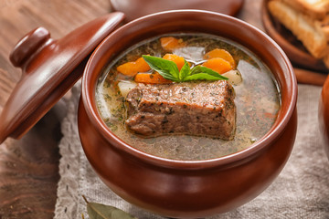 Crock pot with stewed meat on table