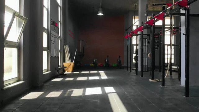 Drone flying low in empty gym towards some rowers and kettlebells (slow motion)