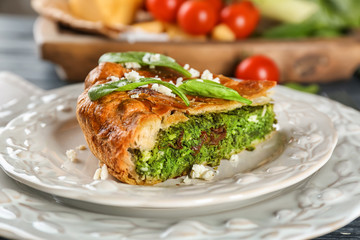 Piece of tasty pie with spinach on plate, close up