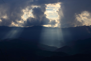 Dramatic god lights passing through clouds and shining on mountain ranges. warm light shower. God...