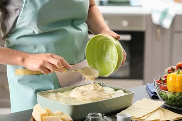 Foto op Canvas Woman cooking spinach lasagna in kitchen © Africa Studio