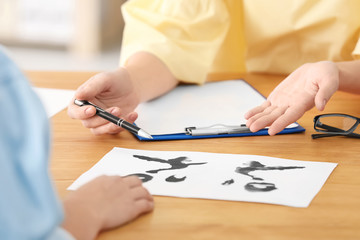Female psychologist showing her patient picture for Rorschach test in office, closeup