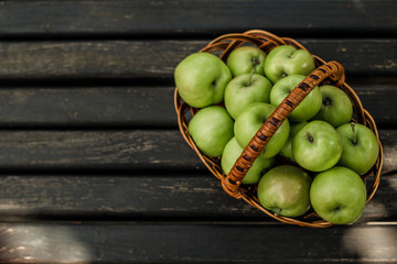 Basket with green apples on a dark wooden background. View from above. Wallpaper. Backround