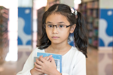 Equal learning opportunity and accessibility in education concept with Asian student kid holding book in library