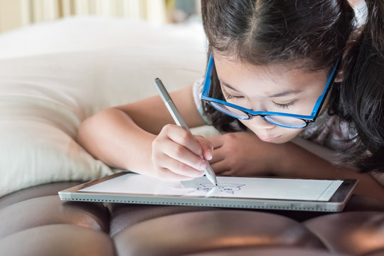 Asian school child girl using smart  tablet device digital technology drawing on innovative touchscreen surface