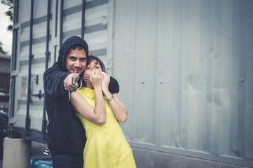 The bandit locks the woman's neck by his arm for a hostage and pointing knife forward. he wear...
