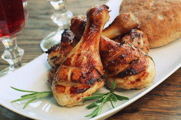Grilled chicken legs with rosemary served on white plate. Dinner background
