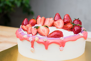 Fresh slice strawberry fruit heart shape decoration on vanilla whipping cream cake with pink sauce star shape topping. Homemade dessert with copy space love valentine, Anniversary concept.