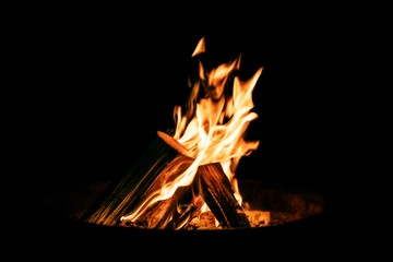 Feuerschale mit brennendem Holz vor Hintergrund Schwarz, Flammen und Feuer
