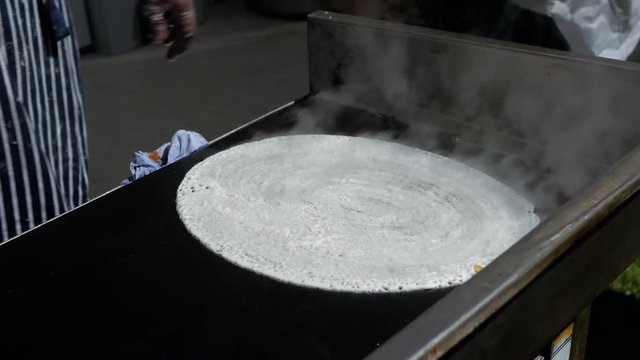 Chef from Rishis Glasgow making dosa on a large pan at Glasgow Mela