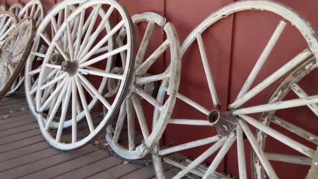 Several old Wooden Wagon wheels all lined up along a wall