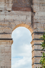 Coliseum in Rome, Italy. Architectural details on a facade. The blue sky is shown through an arch.