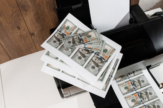 Printer and printed US dollars, counterfeit banknotes, currency counterfeiting. Counterfeiters, printing press, inflation.