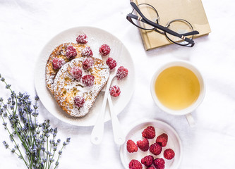 Brioche french toast with raspberry, powdered sugar and green tea. Cozy home still life, free time rest. On a light background, top view. Flat lay