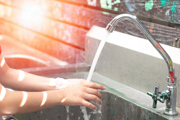 School children hand washing in running water faucet with mess up paint in art class in school.