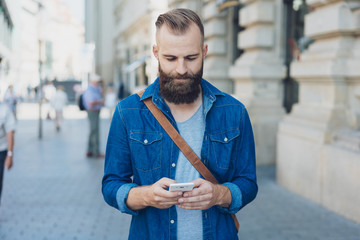 Man standing texting on a mobile on a city street