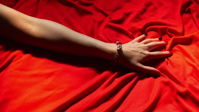 A beautiful female hand touches the red bed.