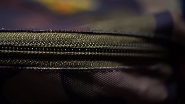 Close up shot of a hand pulling the zip to open a bag