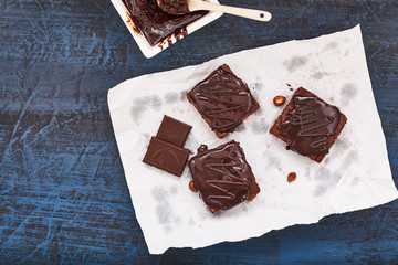 homemade chocolate brownies on dark blue background, top view