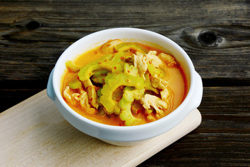 Thai Chicken Curry with Bitter Gourd in white bowl on wooden background.
Chinese bitter melon with coconut and curry soup.